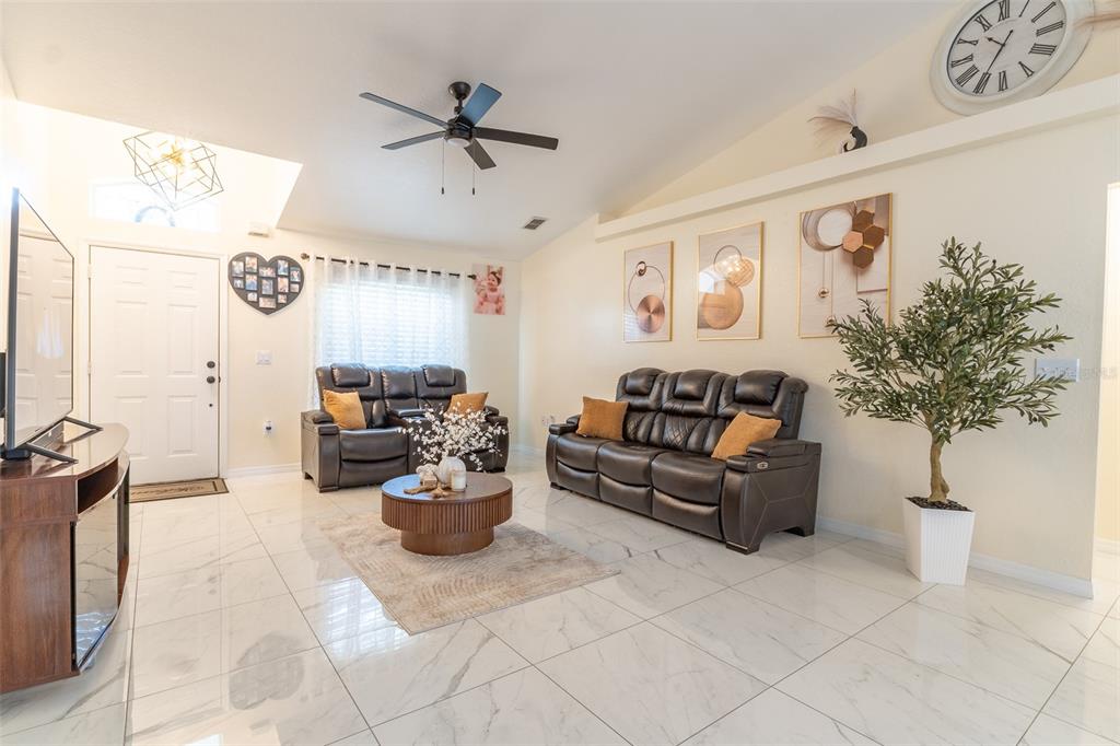 A living room features white marble tile floors, dark leather furniture, and a vaulted ceiling — 930 HICKS ROAD, LAKELAND, FL