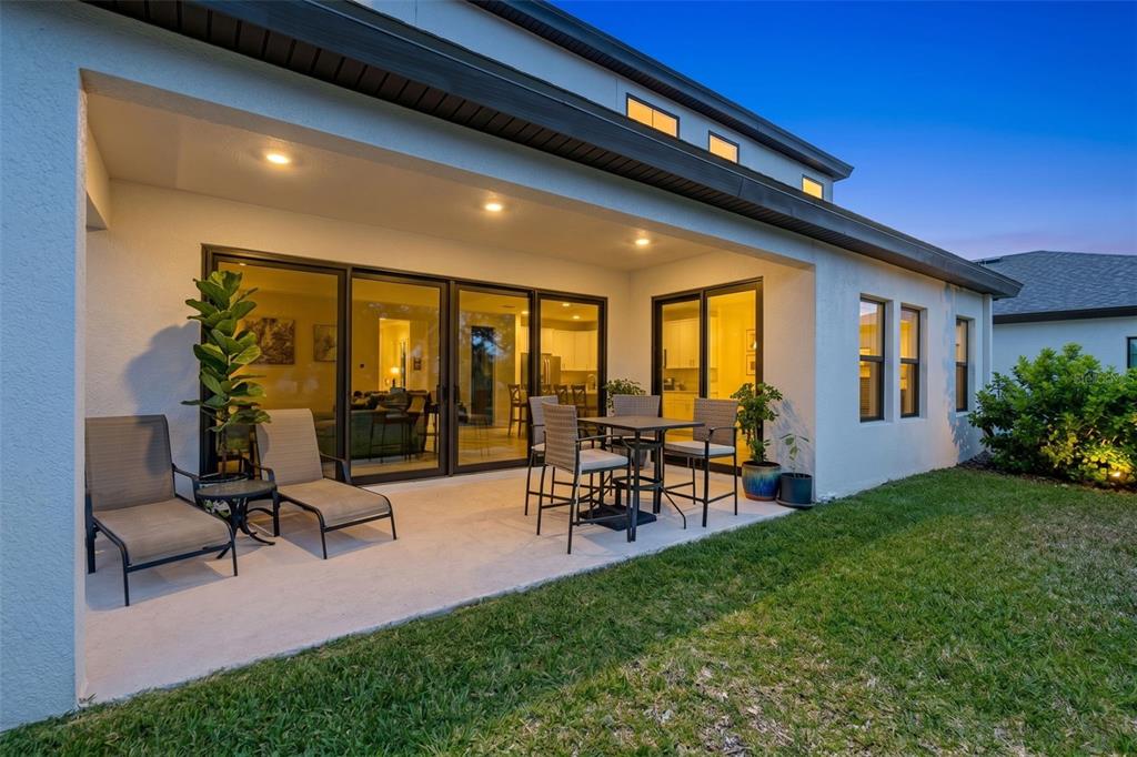 A covered concrete patio features outdoor furniture and sliding glass doors leading into a house — 14868 SUMMER BRANCH DRIVE, LITHIA, FL