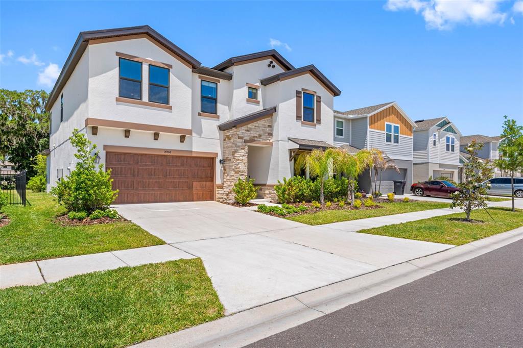 A two-story suburban house with a stucco exterior, stone accents, and a two-car garage — 14868 SUMMER BRANCH DRIVE, LITHIA, FL