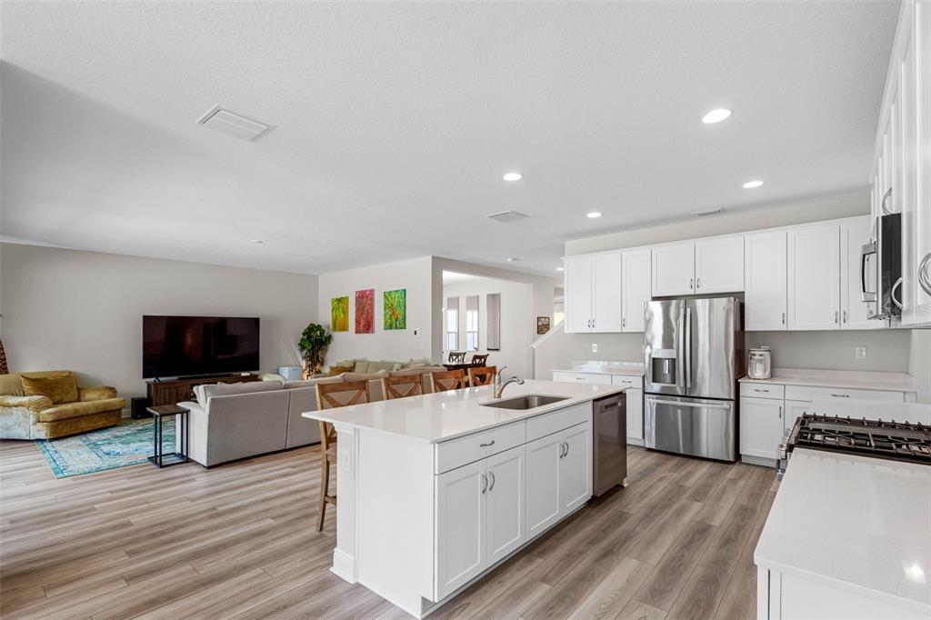 An open-concept kitchen with white cabinets and a central island overlooks a living room area — 14868 SUMMER BRANCH DRIVE, LITHIA, FL