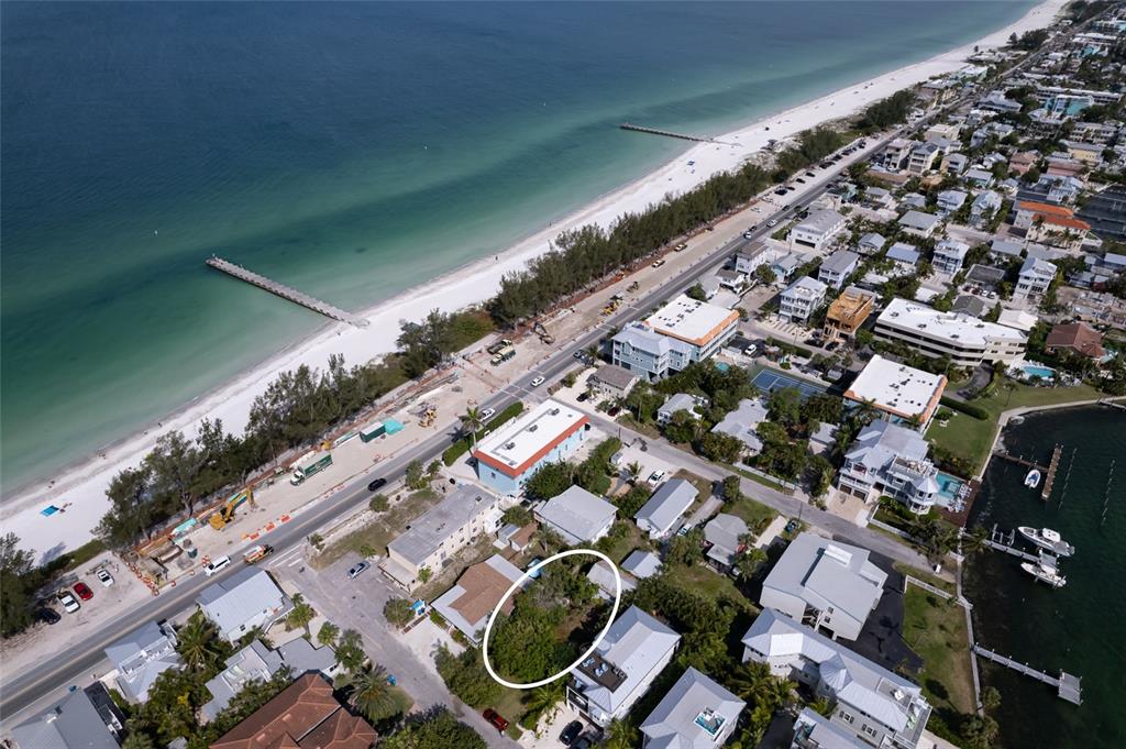 An aerial view shows a vacant, tree-covered lot surrounded by residential buildings near a beach — 106 11TH STREET S, BRADENTON BEACH, FL