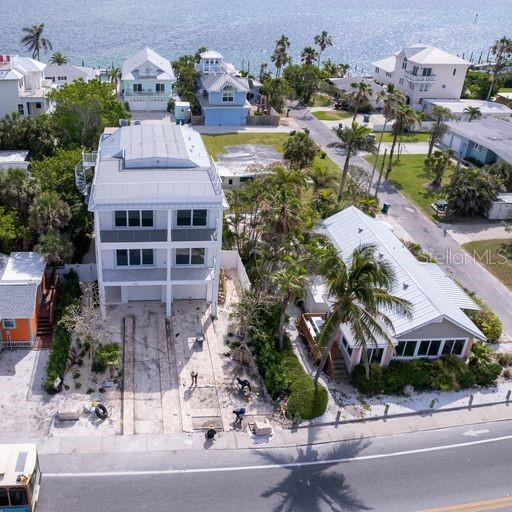 An aerial view shows two coastal houses with metal roofs near a road and water — 106 11TH STREET S, BRADENTON BEACH, FL