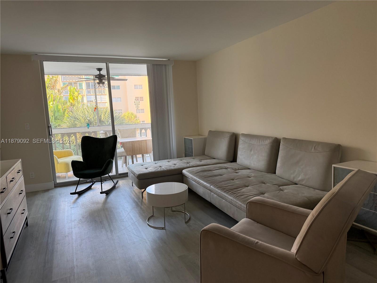 A living room features a sectional sofa, a rocking chair, and a sliding glass door — 901 NE 14th Ave # 305, Hallandale Beach FL 33009, HALLANDALE BEACH, FL