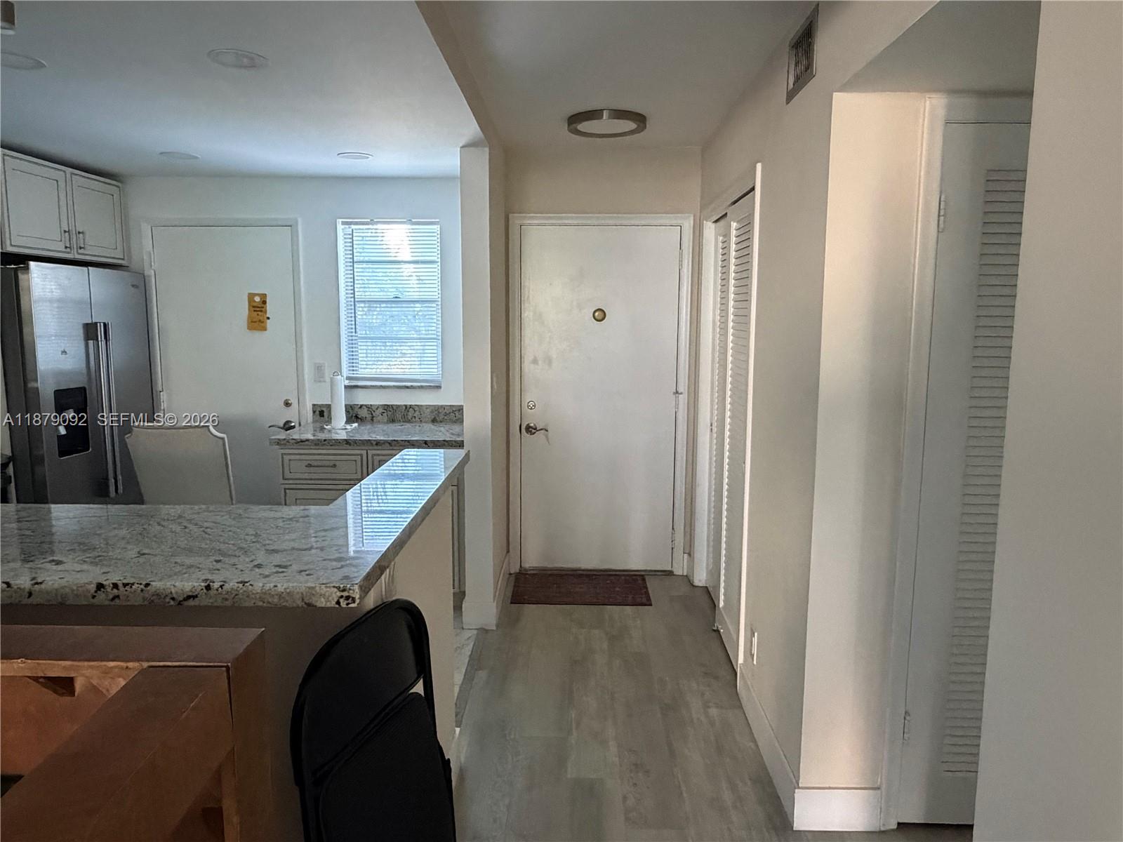 A kitchen with granite countertops and stainless steel appliances leads to an entryway with doors — 901 NE 14th Ave # 305, Hallandale Beach FL 33009, HALLANDALE BEACH, FL