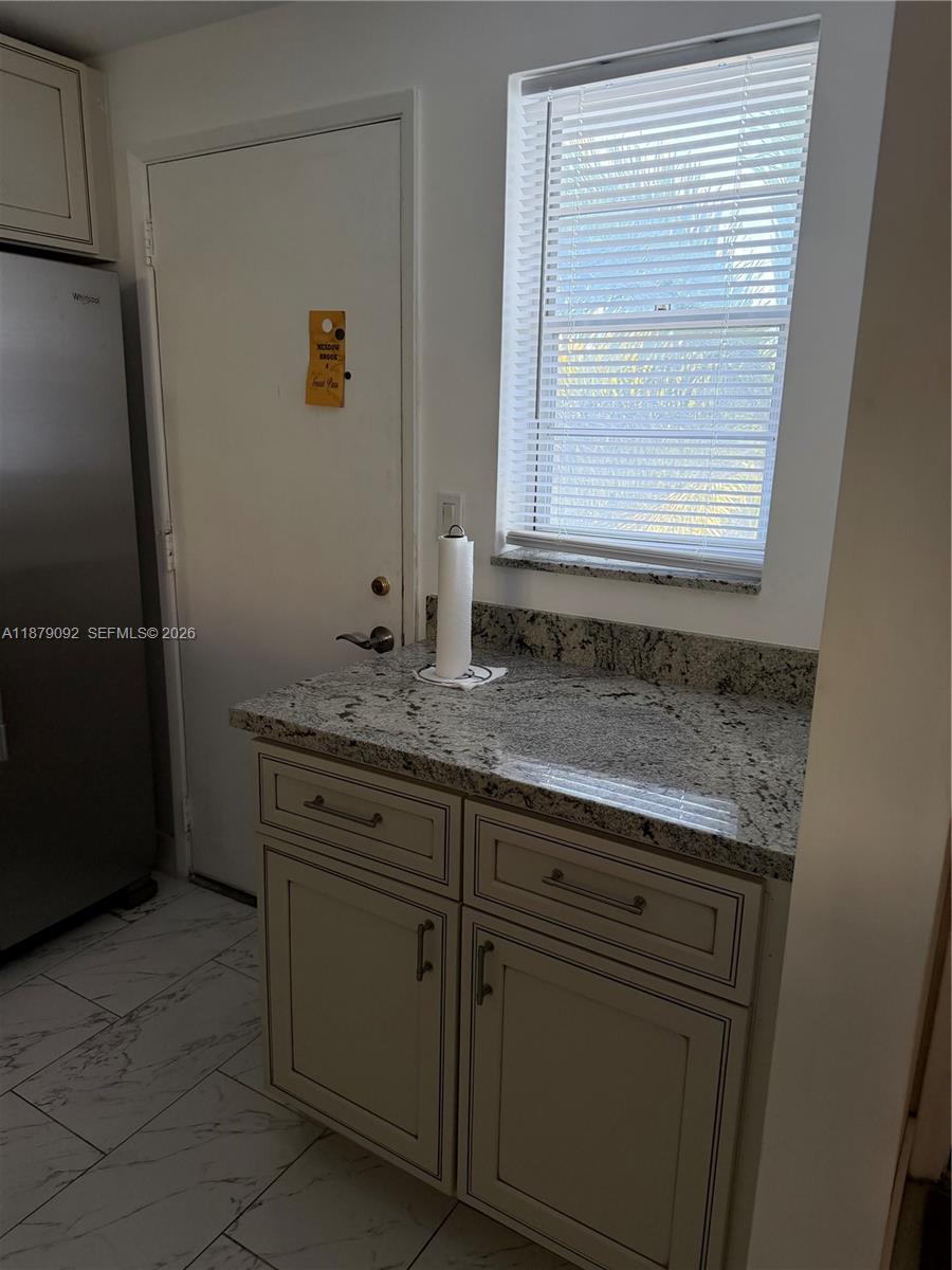 A kitchen corner features a granite countertop, white cabinets, a window with blinds, and a door — 901 NE 14th Ave # 305, Hallandale Beach FL 33009, HALLANDALE BEACH, FL