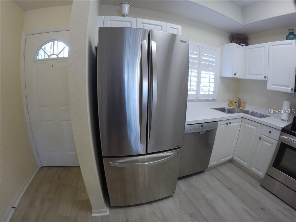 A kitchen features stainless steel appliances, white cabinetry, and light-colored wood-look flooring — 4270 CASTLEBRIDGE LANE UNIT 1714B1, SARASOTA, FL