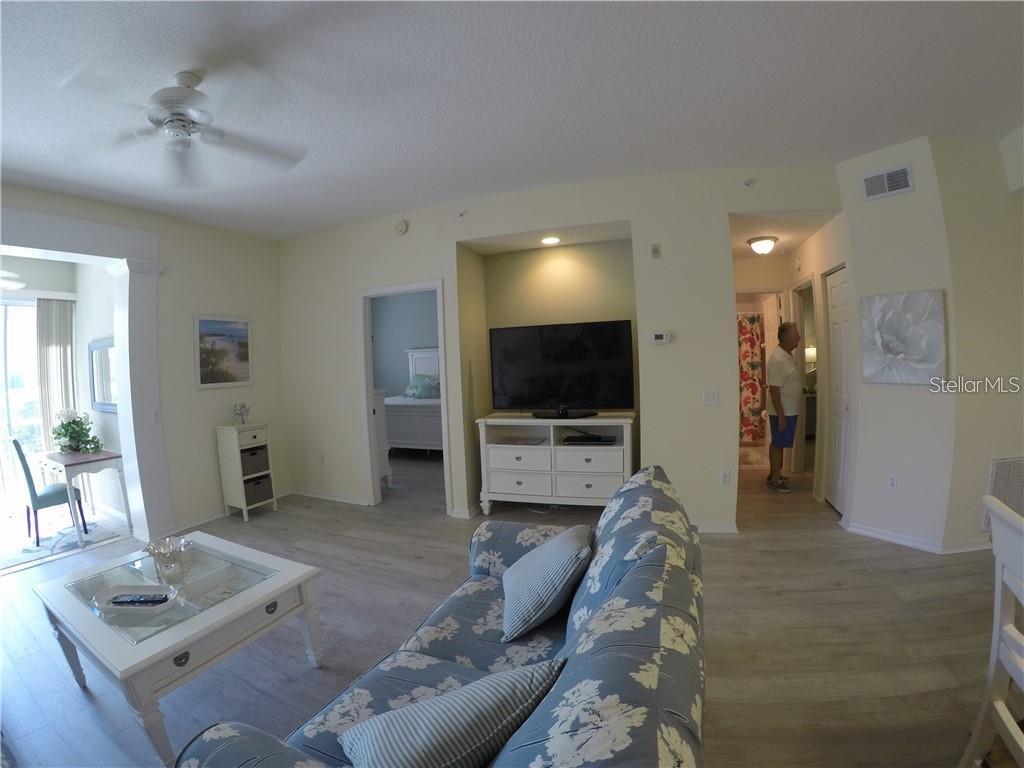A living room features a floral sofa, a white coffee table, and a television console — 4270 CASTLEBRIDGE LANE UNIT 1714B1, SARASOTA, FL