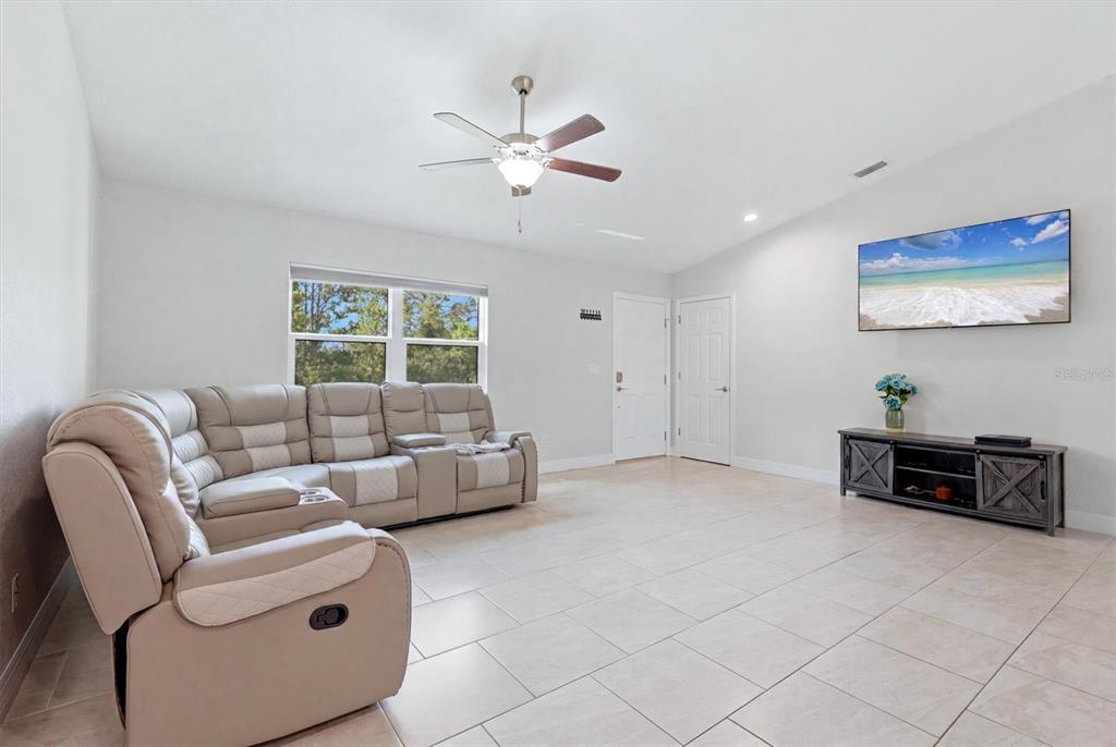 A living room features light-colored tile flooring, a beige sectional sofa, and a wall-mounted television — 1458 RICHBRIAR DRIVE, NORTH PORT, FL