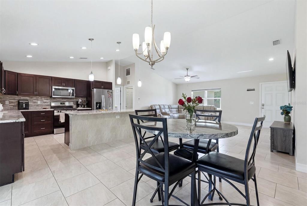 An open-concept kitchen and dining area features dark wood cabinets, granite countertops, and tile flooring — 1458 RICHBRIAR DRIVE, NORTH PORT, FL