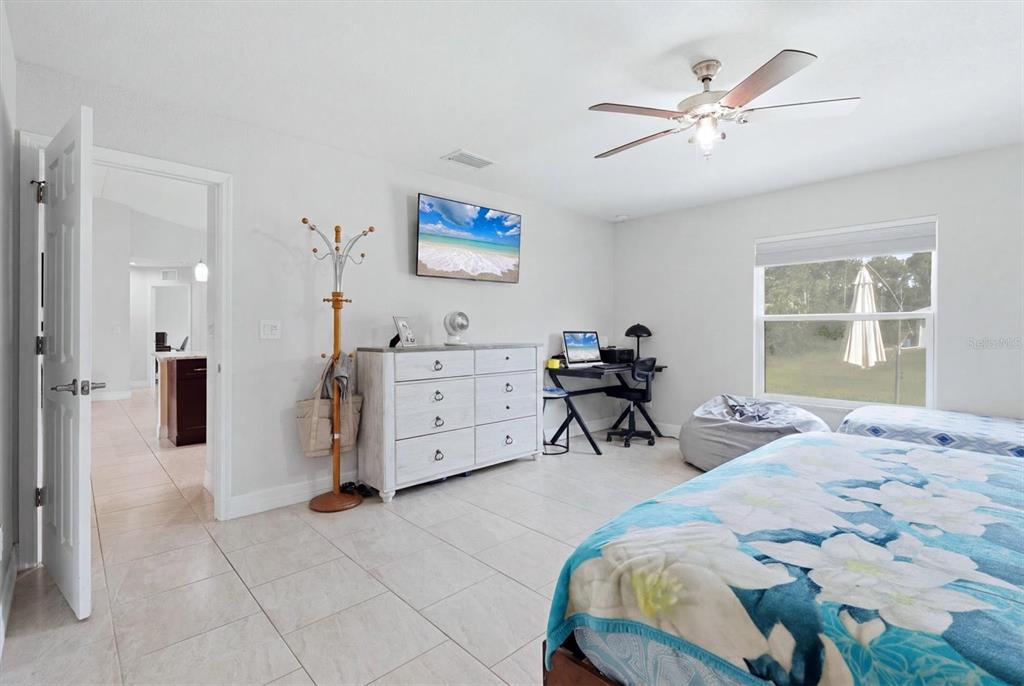 A bedroom features tile flooring, a ceiling fan, a dresser, a desk, and a bed — 1458 RICHBRIAR DRIVE, NORTH PORT, FL