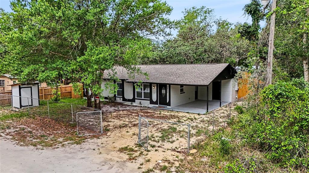 A single-story house with a carport, white exterior, and dark trim sits on a sandy lot — 10131 FIELD STREET, NEW PORT RICHEY, FL