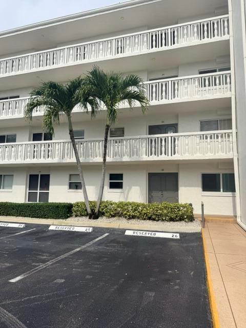 An exterior view of a multi-story apartment building with balconies and reserved parking spaces — 3326 Arcara Way # 108, Lake Worth FL 33467, LAKE WORTH, FL
