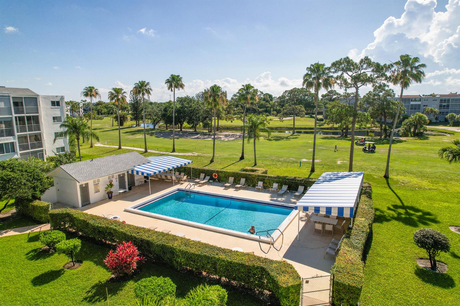 An aerial view of a rectangular swimming pool with blue and white striped awnings — 3326 Arcara Way # 108, Lake Worth FL 33467, LAKE WORTH, FL