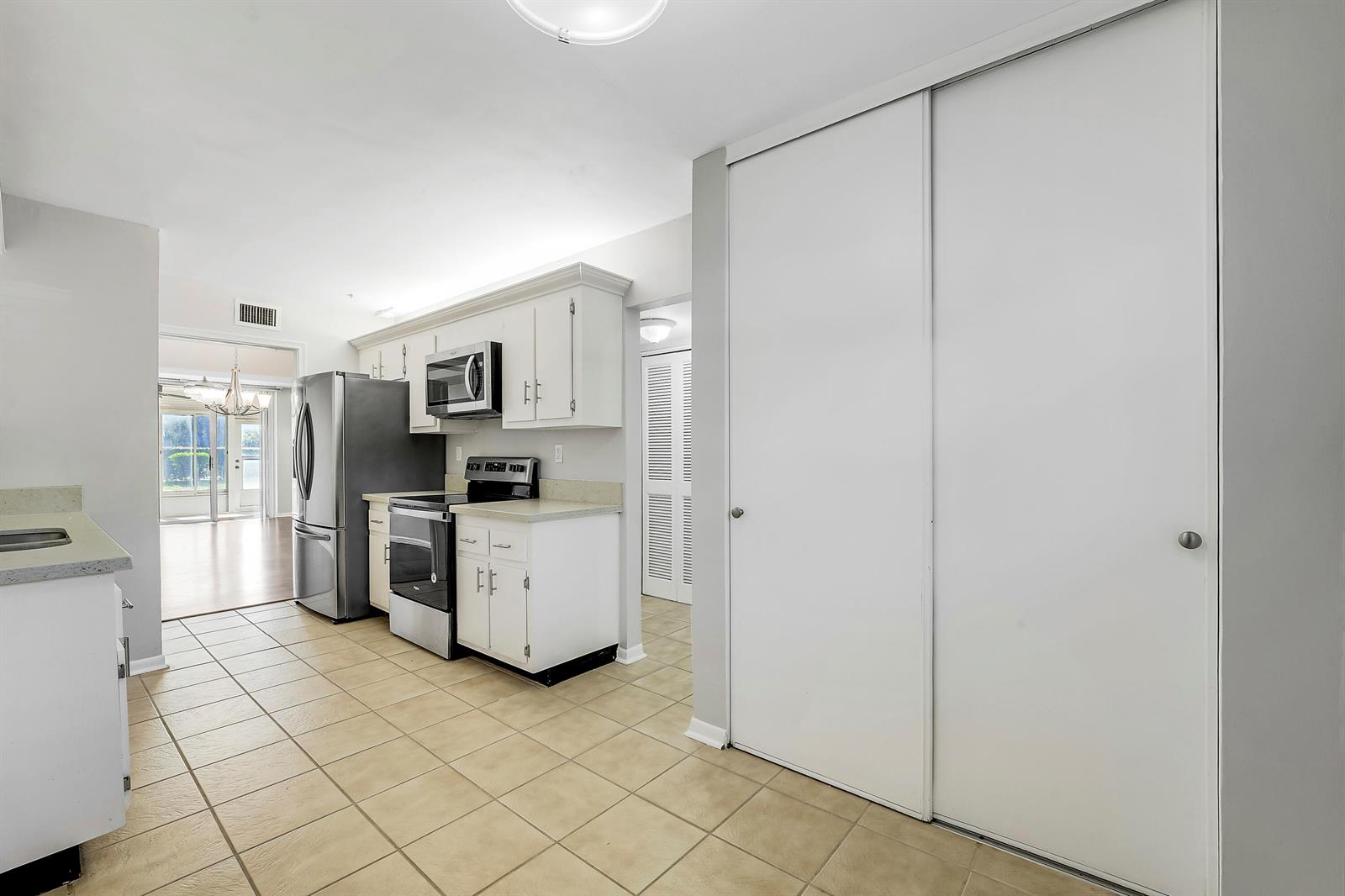A kitchen with white cabinets, stainless steel appliances, tile flooring, and a large sliding closet — 3326 Arcara Way # 108, Lake Worth FL 33467, LAKE WORTH, FL