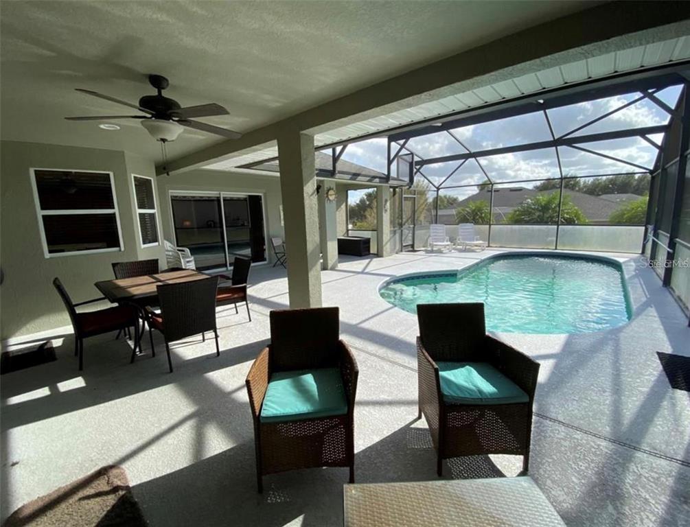 A covered patio features a dining set, lounge chairs, and a screened-in swimming pool — 532 DOLCETTO DRIVE, DAVENPORT, FL