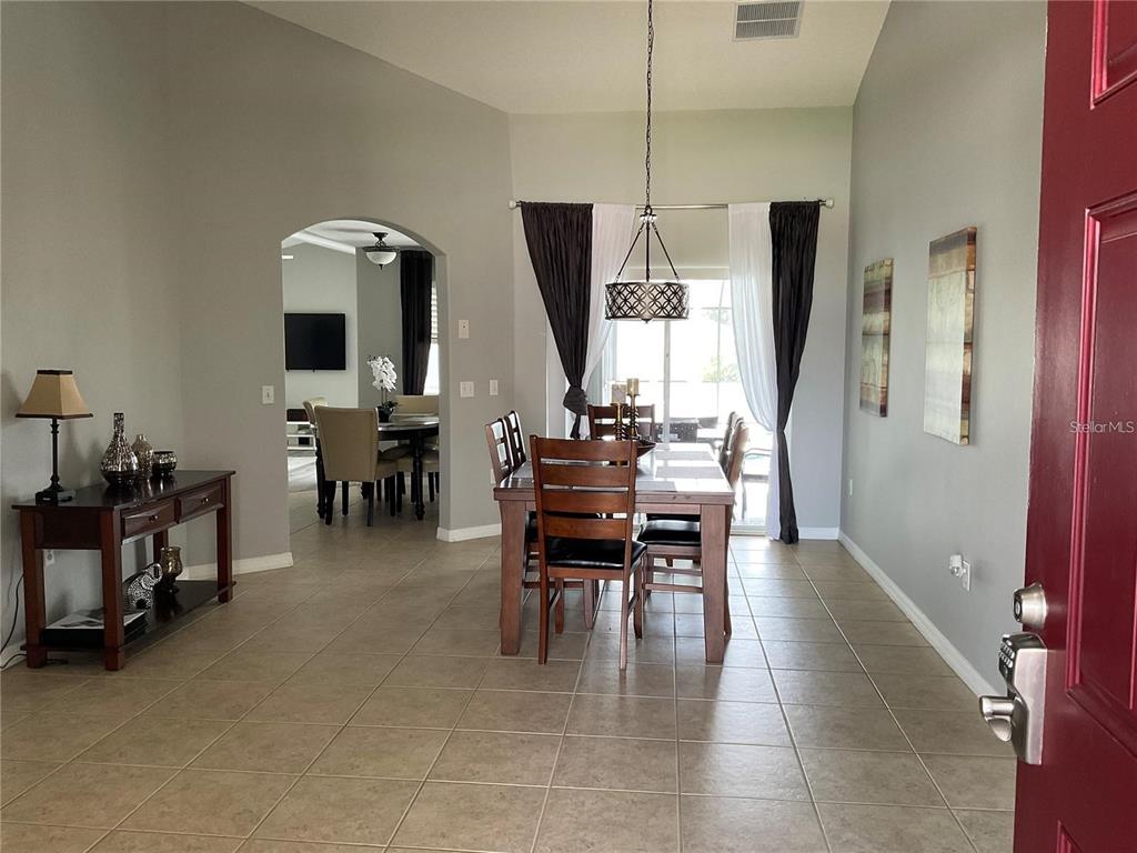 A dining room with tile floors, a wooden table, and a chandelier under a vaulted ceiling — 532 DOLCETTO DRIVE, DAVENPORT, FL