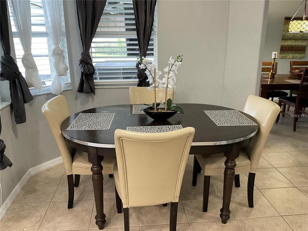 A dining room features a round dark wood table with four cream-colored upholstered chairs — 532 DOLCETTO DRIVE, DAVENPORT, FL