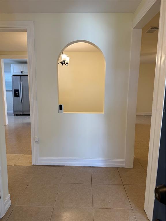 An arched wall cutout separates a tiled entryway from a kitchen with stainless steel appliances — 362 HOLLY RIDGE ROAD, WINTER HAVEN, FL