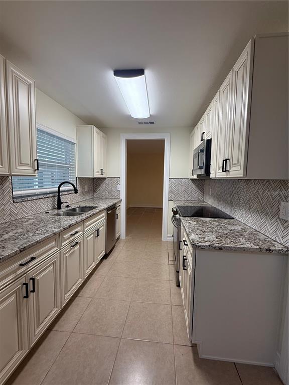 A galley kitchen features white cabinets, granite countertops, a herringbone backsplash, and tile flooring — 362 HOLLY RIDGE ROAD, WINTER HAVEN, FL