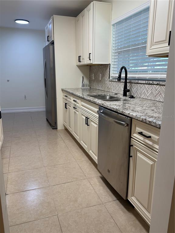 A kitchen features cream-colored cabinets, granite countertops, stainless steel appliances, and a herringbone tile backsplash — 362 HOLLY RIDGE ROAD, WINTER HAVEN, FL
