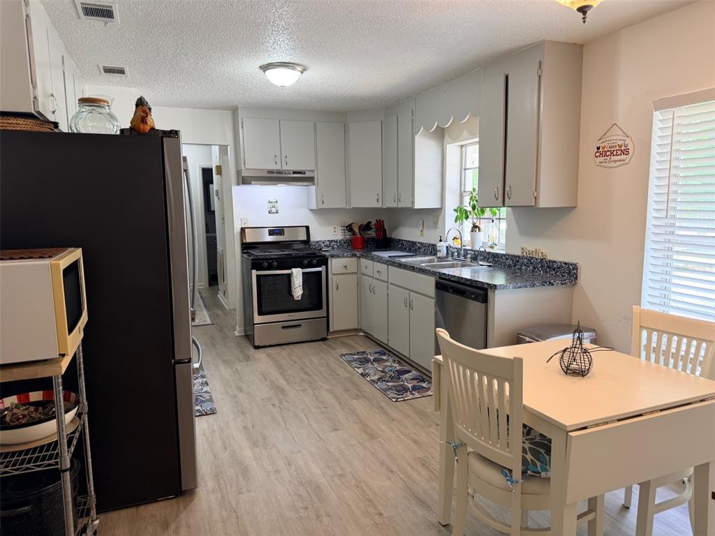 A kitchen with light gray cabinets, stainless steel appliances, and a small dining table — 288 NE 899TH STREET, OLD TOWN, FL