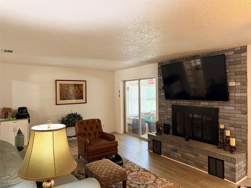 A living room features a brick fireplace with a mounted television and a leather armchair — 288 NE 899TH STREET, OLD TOWN, FL