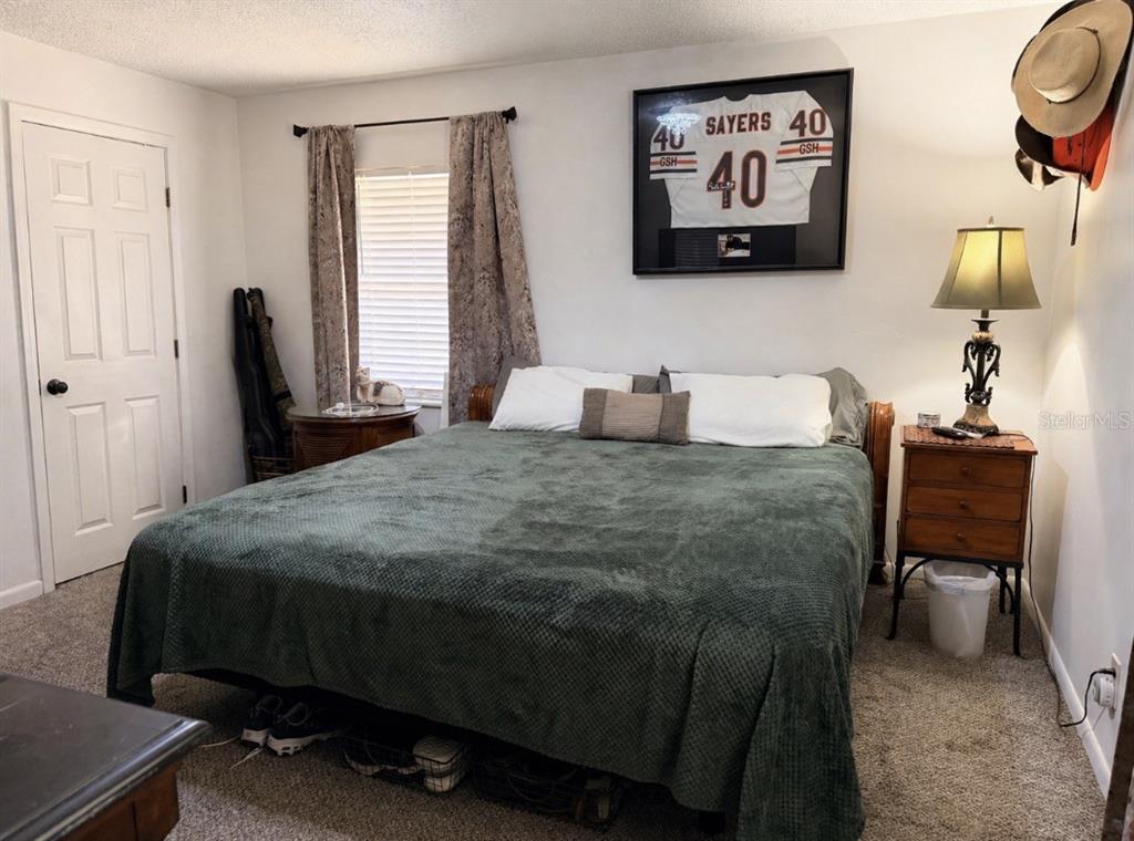 A bedroom features a bed with a green cover, a framed jersey, and a nightstand — 288 NE 899TH STREET, OLD TOWN, FL