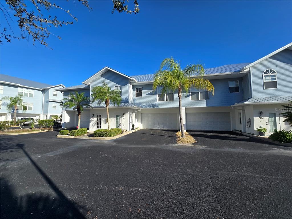 A two-story blue townhouse building features multiple garage doors and palm trees in front — 3919 CAPE HAZE DRIVE UNIT 505, ROTONDA WEST, FL