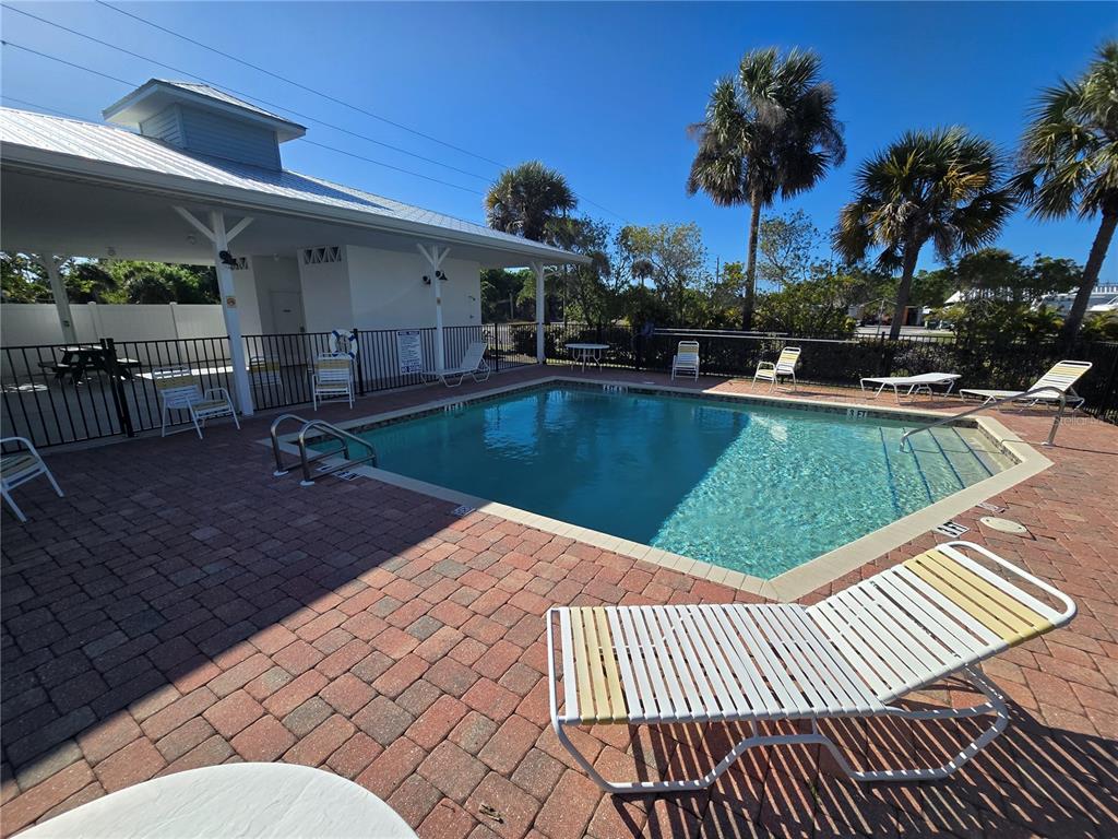 A swimming pool with a brick patio and lounge chairs under a clear blue sky — 3919 CAPE HAZE DRIVE UNIT 505, ROTONDA WEST, FL