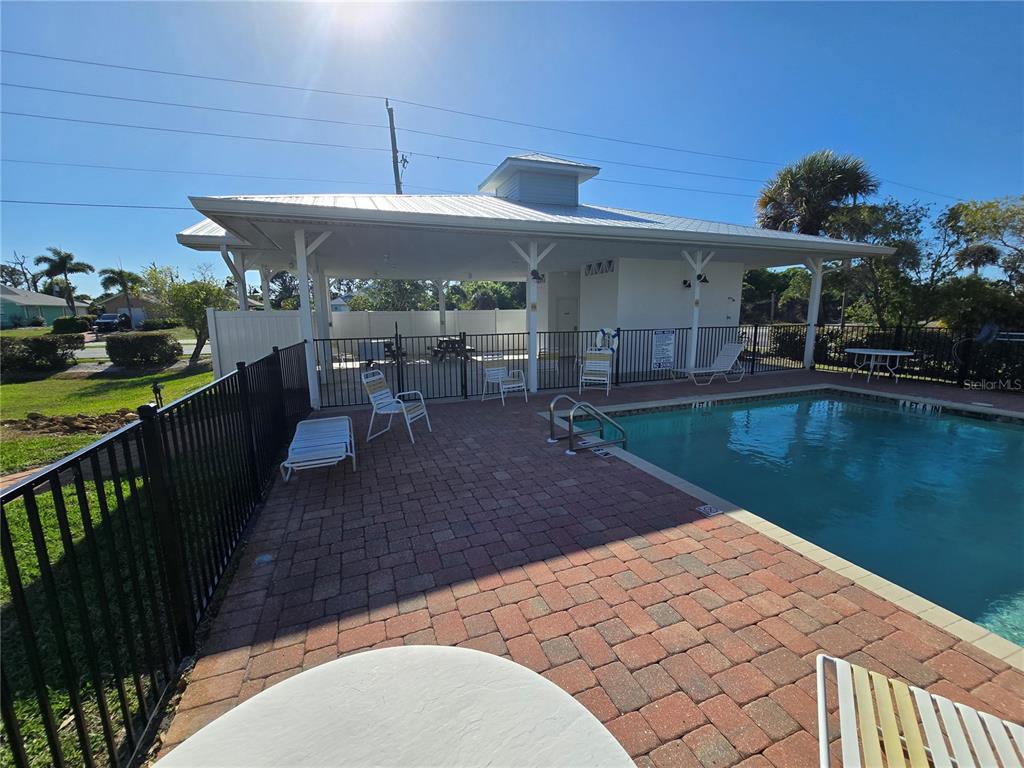 An outdoor swimming pool area features a covered pavilion, brick pavers, and metal fencing — 3919 CAPE HAZE DRIVE UNIT 505, ROTONDA WEST, FL