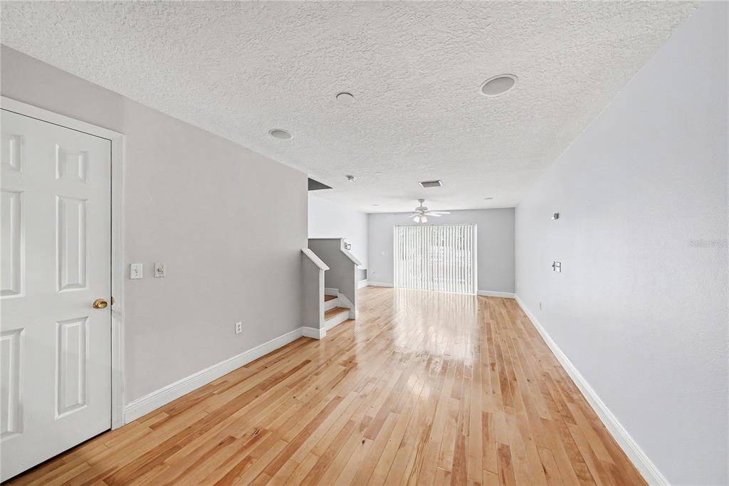 An empty living room features light-colored walls, hardwood flooring, recessed lighting, and a staircase — 8106 SILENT CREEK DRIVE, TAMPA, FL
