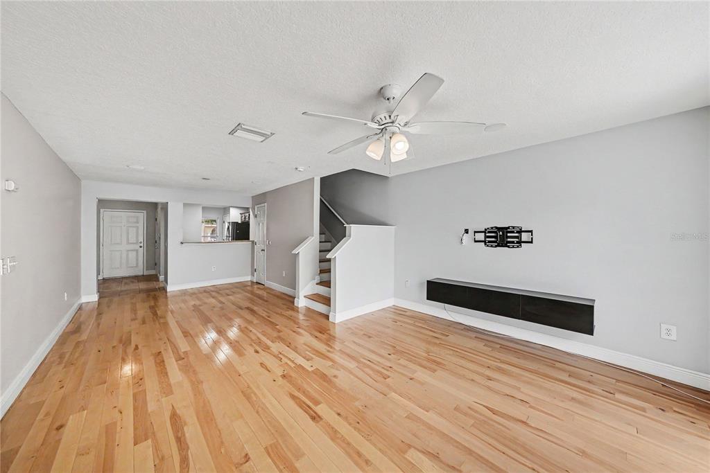 A living room with hardwood floors, a ceiling fan, a staircase, and a wall-mounted console — 8106 SILENT CREEK DRIVE, TAMPA, FL