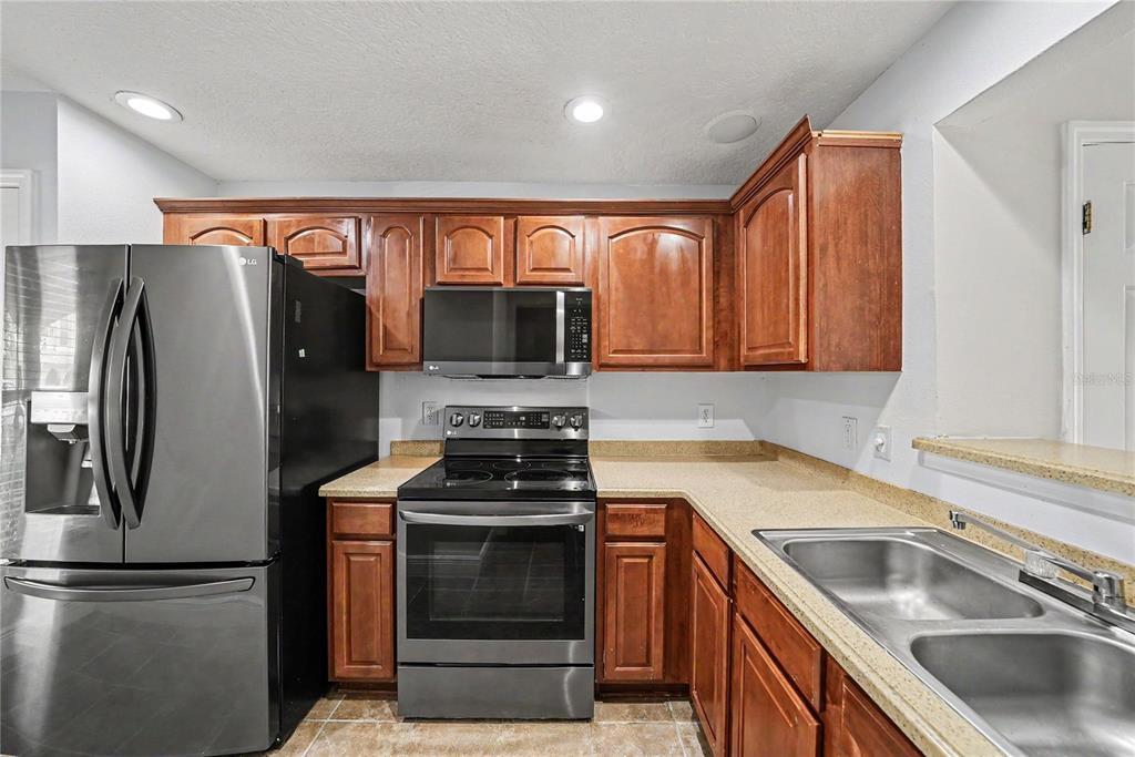 A kitchen features wood cabinets, stainless steel appliances, and tan countertops — 8106 SILENT CREEK DRIVE, TAMPA, FL