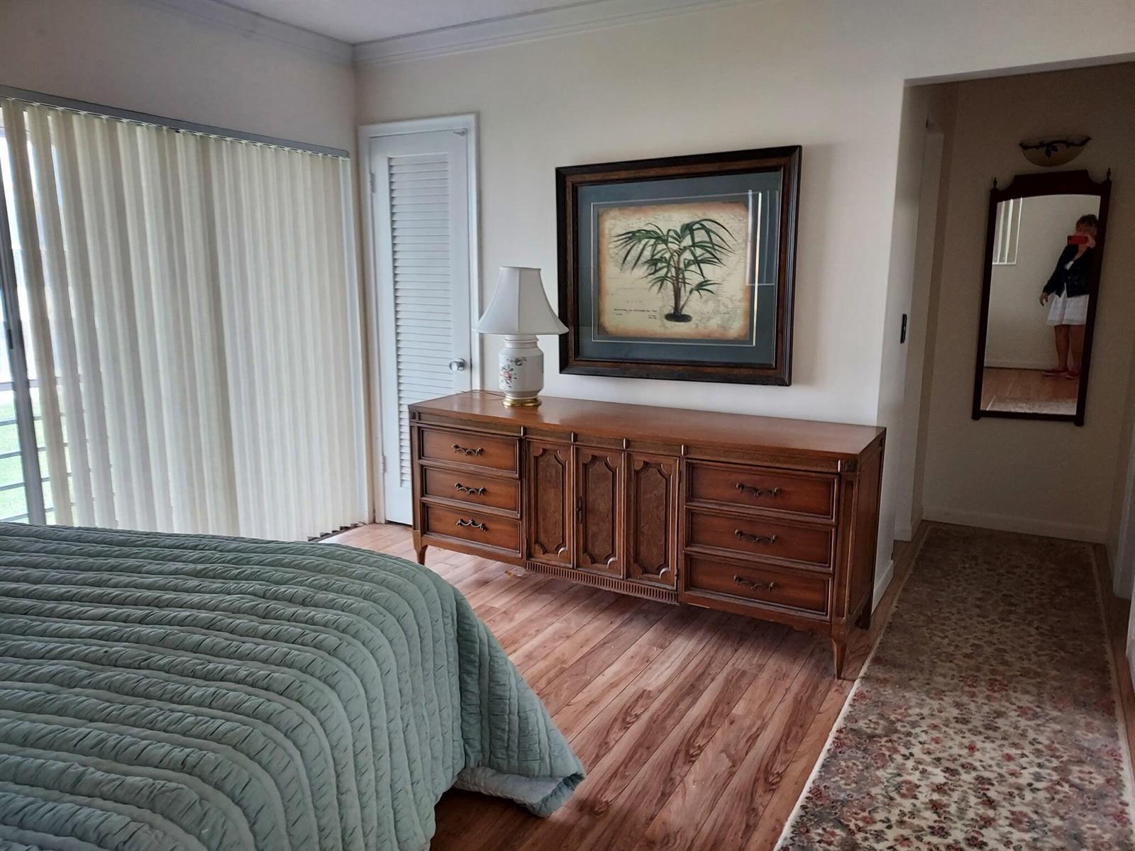 A bedroom features a wooden dresser, a framed palm print, and a green quilted bedspread — 261 Coventry K, West Palm Beach FL 33417, WEST PALM BEACH, FL