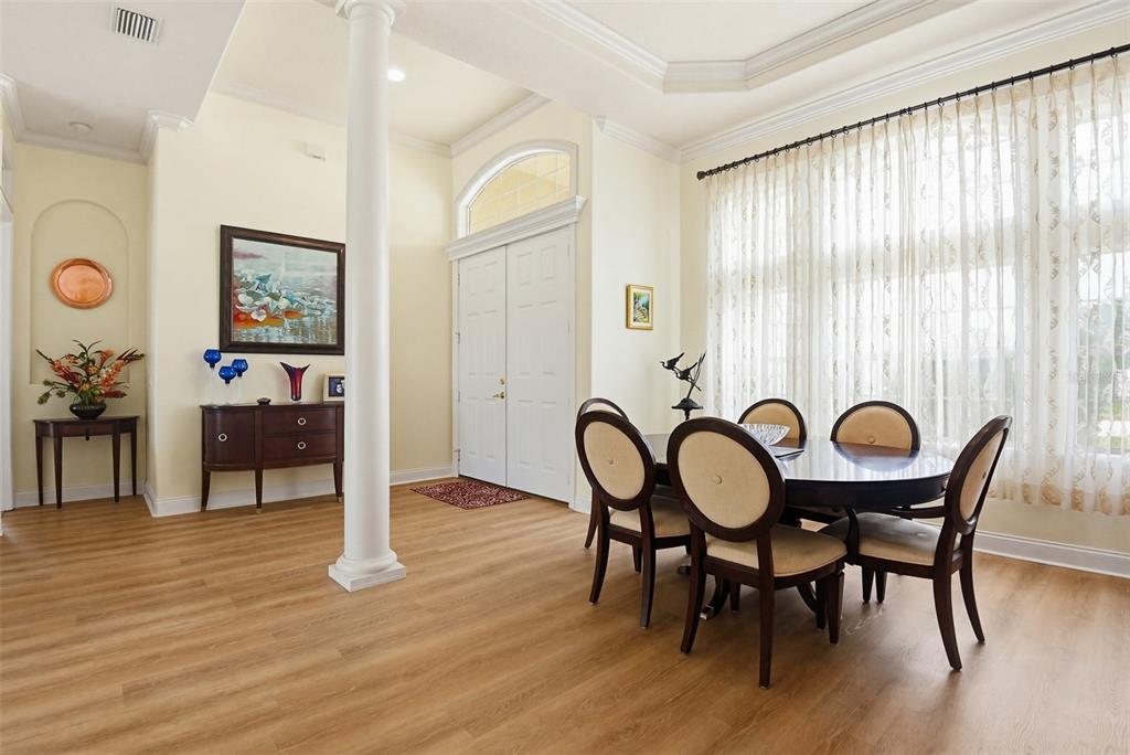 A dining area with wood-look flooring, a white pillar, and a large window with curtains — 9 LONDON DR, PALM COAST, FL