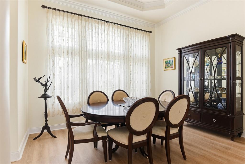 A dining room features a dark wood table, matching chairs, and a large glass-front cabinet — 9 LONDON DR, PALM COAST, FL