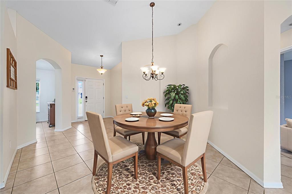 A dining area features a round wooden table, four upholstered chairs, and a chandelier — 6568 SW 129TH LANE, OCALA, FL