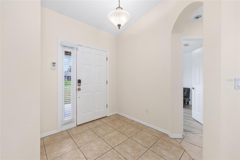 An entryway features beige tile flooring, a white front door with sidelights, and a light fixture — 6568 SW 129TH LANE, OCALA, FL