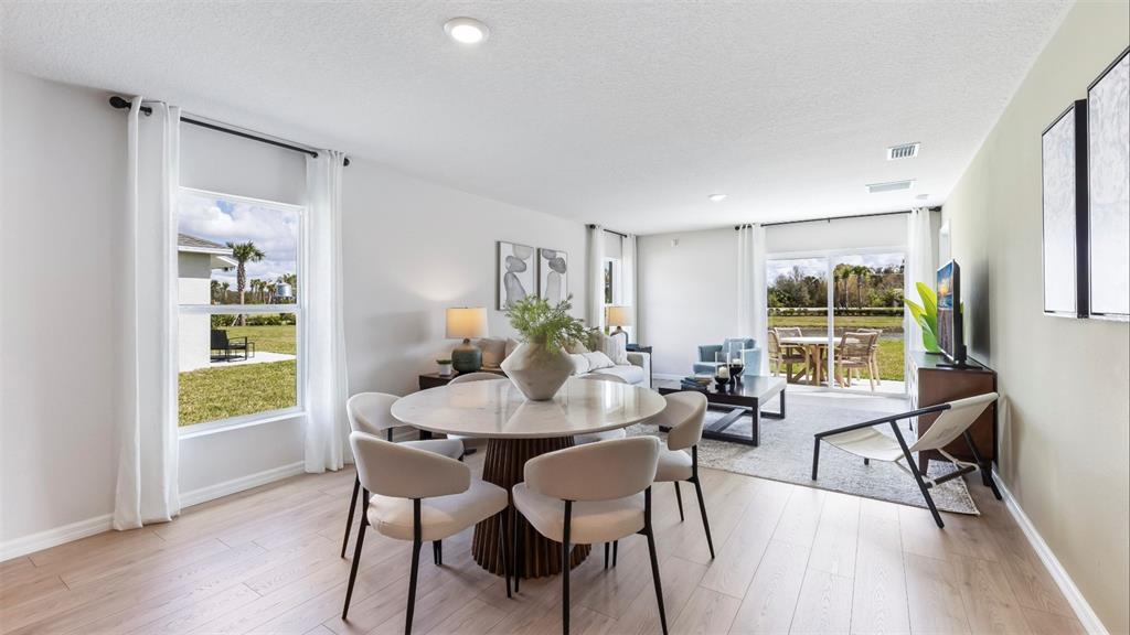 A dining area with a round table opens into a living room with sliding glass doors — 13133 OLD CANOE WAY, PARRISH, FL
