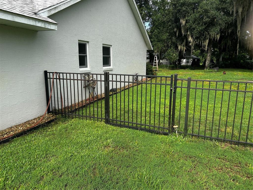 A black metal fence runs along the side of a house with a grassy yard — 1109 S CHATEAU POINT, INVERNESS, FL