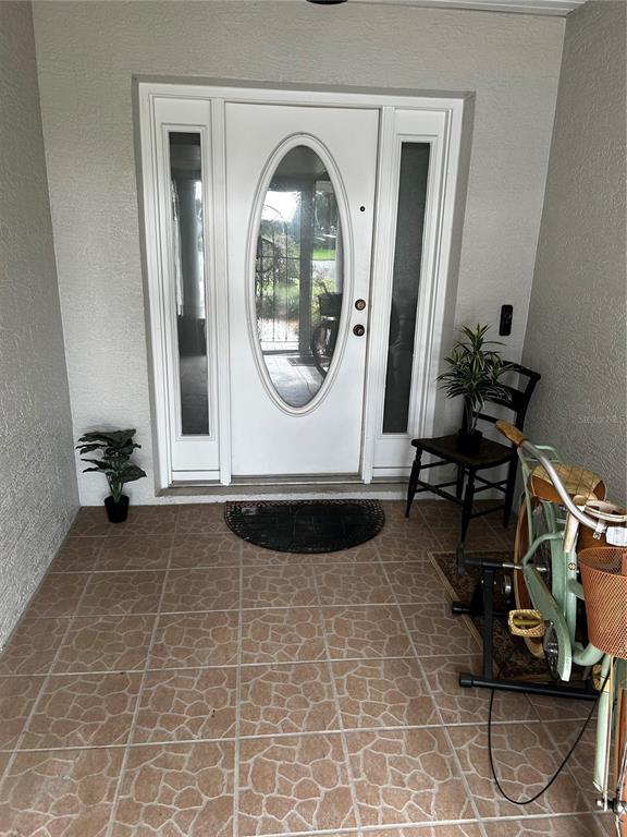 A white front door with an oval glass insert sits on a tiled porch — 1109 S CHATEAU POINT, INVERNESS, FL
