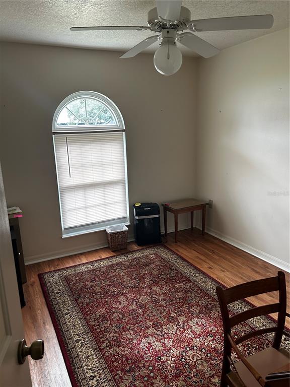 A room with wood-look flooring, a ceiling fan, an arched window, and a patterned rug — 1109 S CHATEAU POINT, INVERNESS, FL