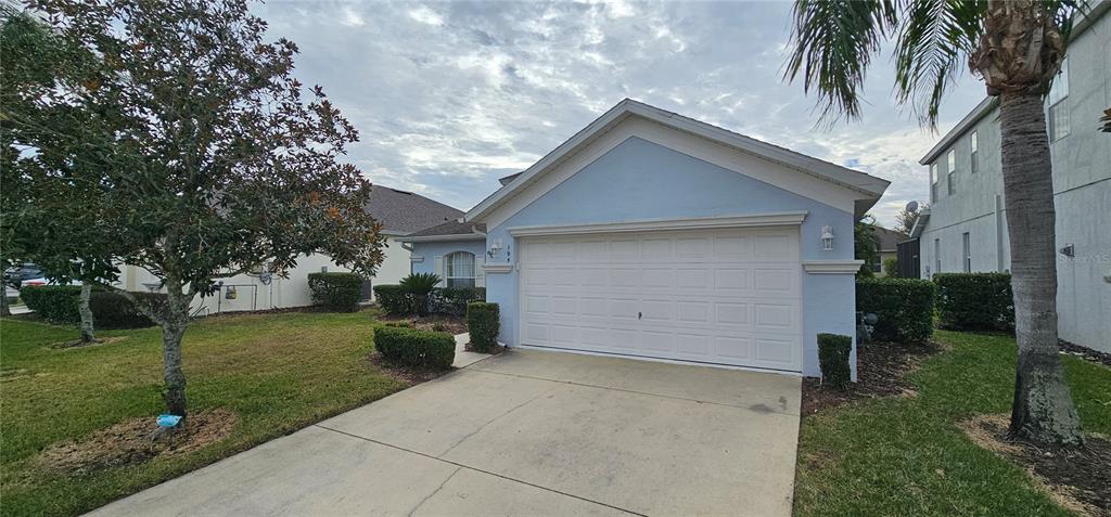 A light blue house with a white garage door and a concrete driveway — 195 MINNIEHAHA CIRCLE, HAINES CITY, FL