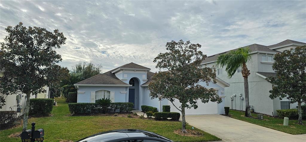 A light blue single-story house features a driveway, a two-car garage, and mature landscaping — 195 MINNIEHAHA CIRCLE, HAINES CITY, FL