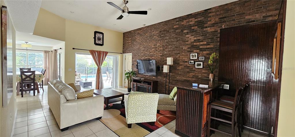 A living room features a brick accent wall, a ceiling fan, and a bar area — 195 MINNIEHAHA CIRCLE, HAINES CITY, FL