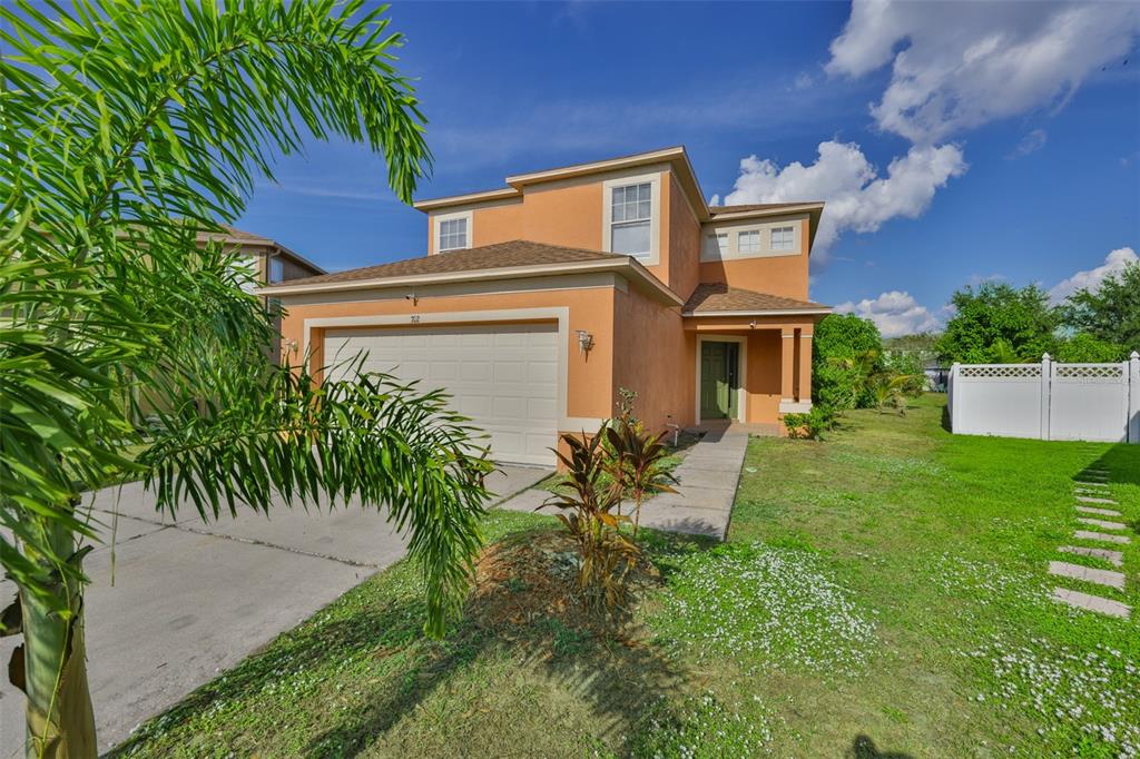 A two-story orange stucco house with a two-car garage and a front yard — 702 CRISTELLE JEAN DRIVE, RUSKIN, FL