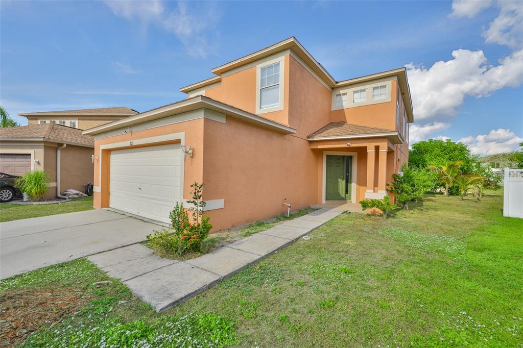 A two-story, orange stucco house with a garage and a green front door — 702 CRISTELLE JEAN DRIVE, RUSKIN, FL