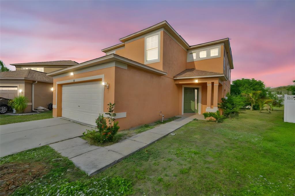 A two-story orange stucco house with a two-car garage and a green front door — 702 CRISTELLE JEAN DRIVE, RUSKIN, FL
