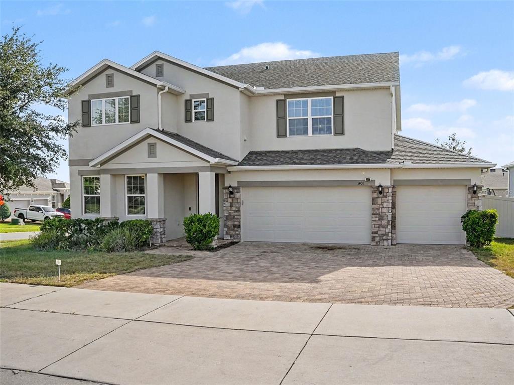 A two-story suburban house features a beige stucco exterior, stone accents, and a paved driveway — 1401 SHIRA ROAD, MINNEOLA, FL