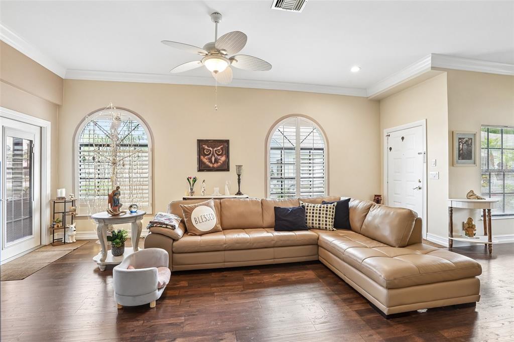 A living room features a tan sectional sofa, wood flooring, and two arched windows — 3878 TANAGER PLACE, PALM HARBOR, FL